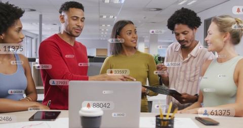 Creative team collaborating around laptop and tablet with social notification badges