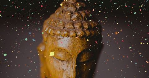 Carved wooden buddha statue with celebratory confetti
