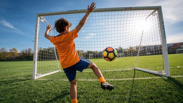 Youth soccer player blocking goal on sunny field