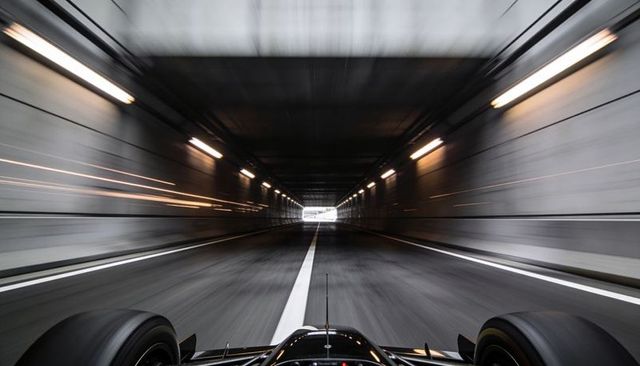 Open-wheel racecar racing through tunnel at high speed with motion blur and centerline