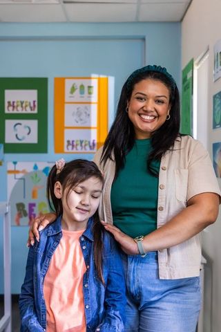 Smiling woman mentoring young girl in colorful recycling classroom, eco education