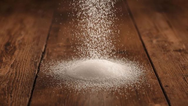 White granular powder falling on rustic wooden table