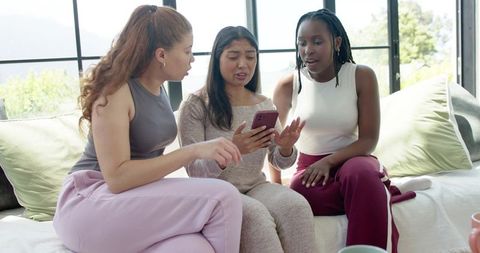 African american friends reacting to smartphone during cozy living room hangout