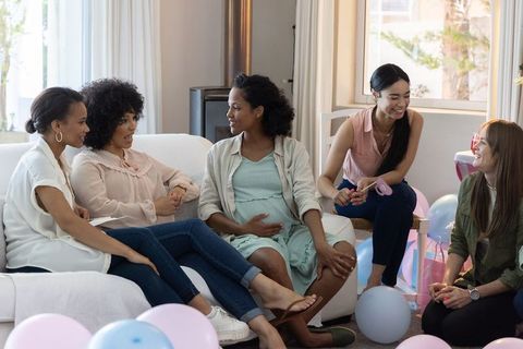 Friends Celebrating Baby Shower with Pastel Decor in Cozy Living Room