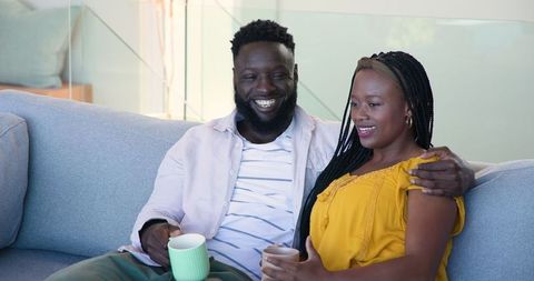 Joyful African American Couple Relaxing on Couch with Coffee