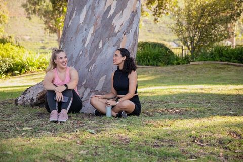 Diverse female friends relaxing in park with activewear
