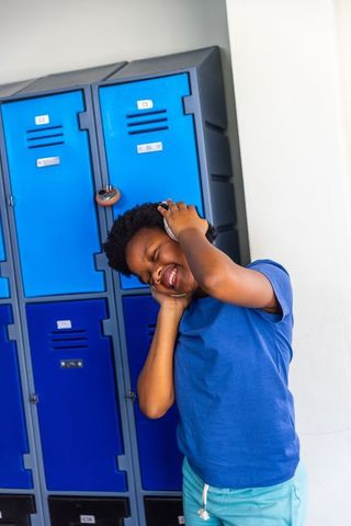 African american boy listening to music with headphones at school lockers