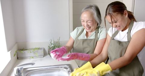 Grandmother and Granddaughter Bonding While Washing Dishes in Kitchen