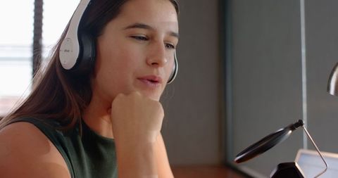 Woman Using Headphones Speaking into Microphone in Home Studio