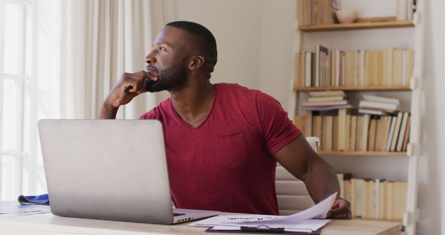 Pensive Man Working from Home on Laptop with Documents - Download Free Stock Images Pikwizard.com