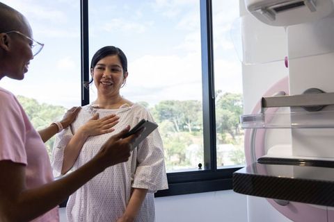 Nurse Guiding Patient Through Mammography Screening While Using Tablet in Bright Clinic