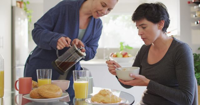 Caucasian woman pouring coffee in a cup while having breakfast with her wife at home. lgbt relationship and lifestyle concept
