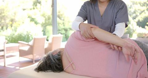 Physiotherapist Assisting Senior Woman with Arm Exercise Therapy