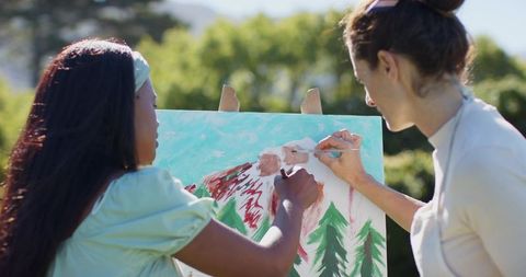 Diverse friends painting landscape outdoors with easel and canvas