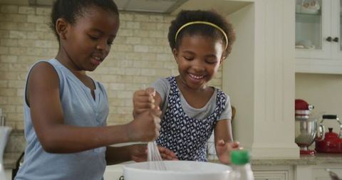Two African American Sisters Joyfully Baking Together in Kitchen