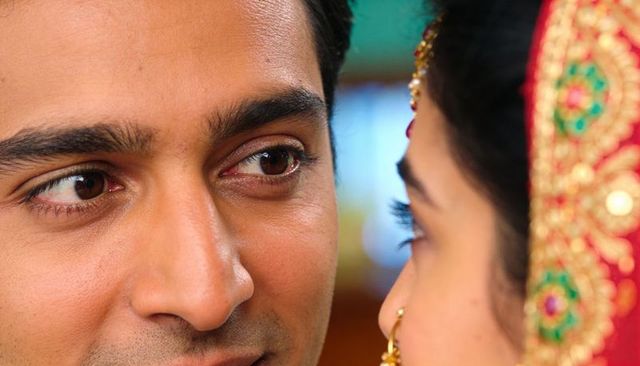 Indian bride and groom gazing closeup with red embroidered dupatta and gold nose ring