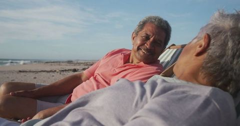 Senior Hispanic Couple Relaxing on Beach at Sunset