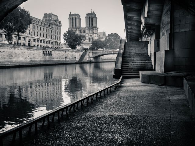 Historic cathedral overlooking river in a monochrome palette, with stone bridge in background and steps leading to water. Ideal for travel magazines, historical blogs, vintage design projects, and architecture enthusiasts highlighting European landmarks.