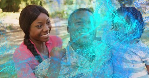 Smiling Parents Holding Son with Turquoise Powder Splash in Sunlit Park Family Joy