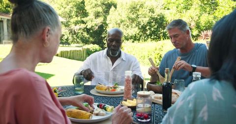 Diverse group enjoying backyard al fresco dining with grilled corn