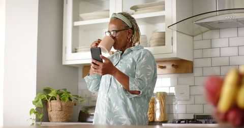 Senior Woman Enjoying Coffee While Checking Smartphone