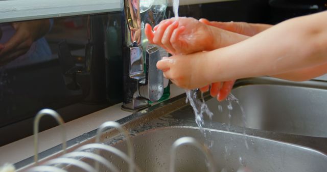 Close-up of mother and daughter washing hands in sink at comfortable home. Water flowing from tap 4k