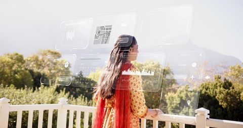 Standing woman in yellow tunic and red scarf gazing at ar panels above balcony