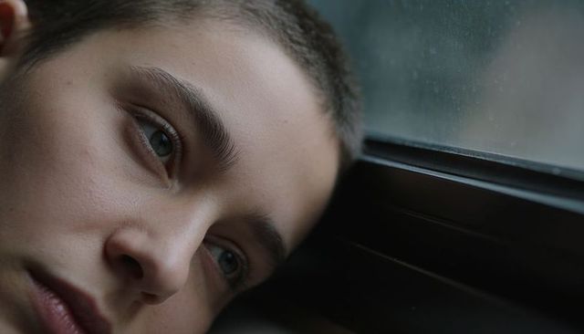 Teen boy gazing through rainy train window closeup conveying melancholy and reflection