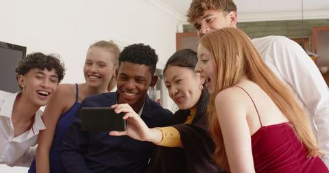 Diverse friends taking selfie in modern home kitchen during celebration