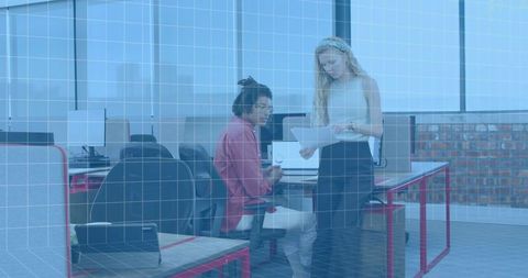 Coworkers Reviewing Documents in Open-Plan Office Collaborating Over Laptop and Papers