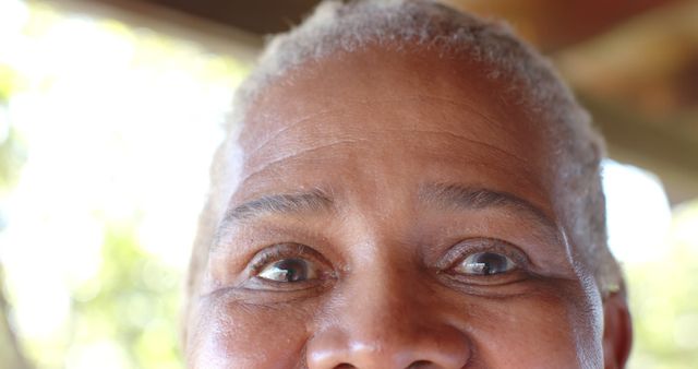 Eyes of happy senior african american woman standing on sunny porch. Retirement, summer, relaxation, domestic life and senior lifestyle, unaltered.