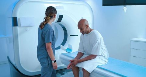 Male patient sitting on mri table while technologist preparing for diagnostic scan