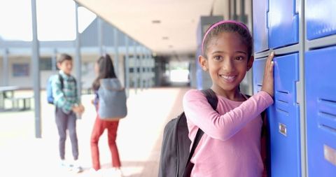 Young Female Student Opening Locker in School Hallway