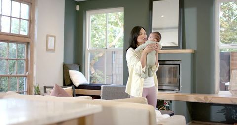 Asian Mother Embracing Infant Daughter in Cozy Living Room