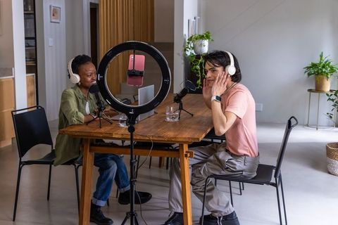 Diverse duo recording podcast at home studio with ring light and microphones