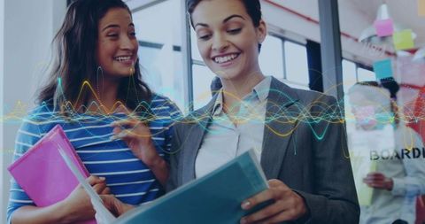 Smiling colleagues reviewing documents with colorful waveform overlay representing teamwork