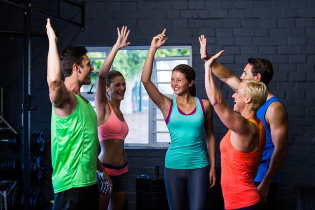 Group of athletes celebrating their success with high-fives in a gym. Perfect for promoting teamwork, fitness programs, gym memberships, and motivational content. Ideal for use in advertisements, social media posts, and fitness blogs.