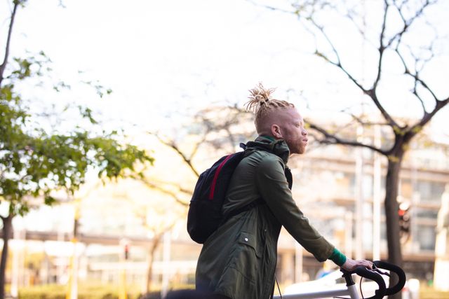 Albino young man riding bicycle on urban street, showcasing active and healthy lifestyle. Ideal for use in articles about albinism, urban commuting, healthy living, and inclusivity. Can be used in promotional materials for outdoor activities, city transportation, and lifestyle blogs.
