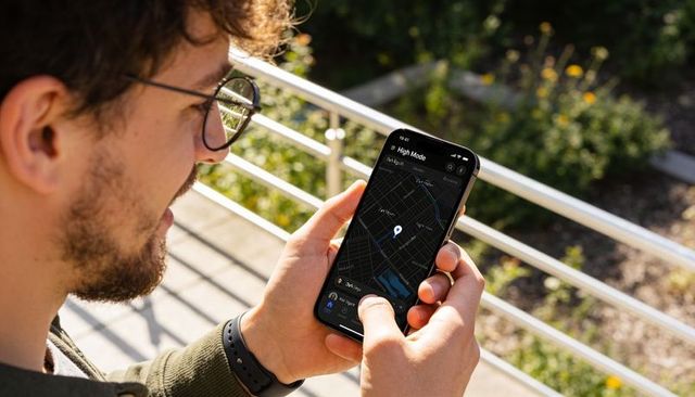 Young man checking navigation map on smartphone by park railing in golden sunlight