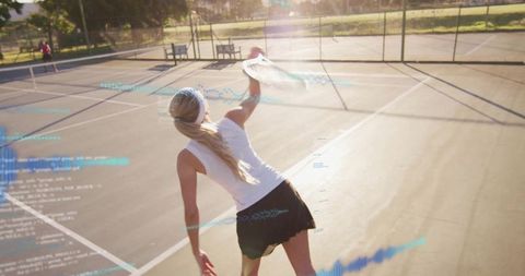 Female tennis player serving on sunlit outdoor court