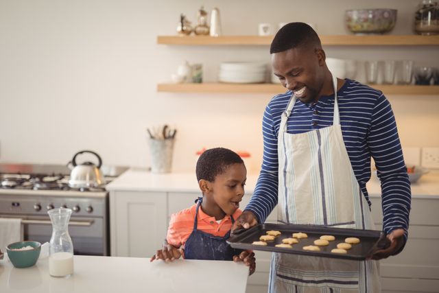 Smiling father holding tray while son looking at cookies