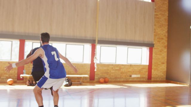 Players are dribbling and actively participating in an indoor basketball match, highlighting athleticism and teamwork. Useful for promoting sports events, athletic gear, or basketball training programs.