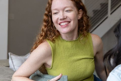 Red-haired woman smiling on sofa holding cushion casual home interior lifestyle portrait