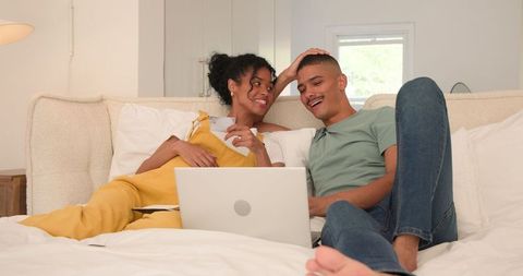 Couple having fun watching content on laptop in bedroom