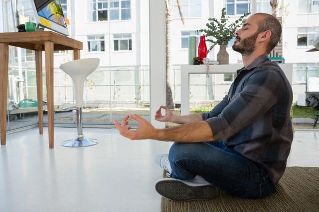 Side view of businessman meditating while sitting on floor at office