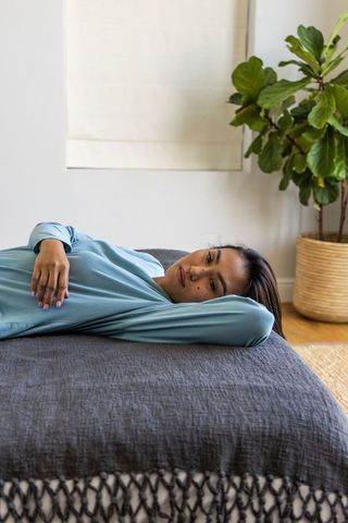 Asian woman relaxing on bed in minimalist bedroom with indoor plant and cozy bedding