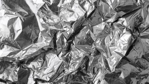 Crumpled aluminum foil reflecting light macro metallic texture with sharp creases