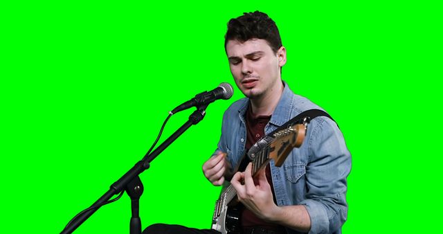 Male musician singing while playing guitar against green screen - Download Free Stock Photos Pikwizard.com