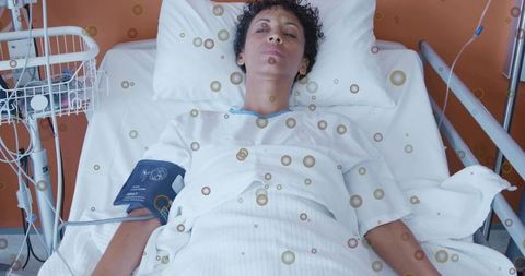 Mature woman receiving iv infusion in hospital bed with vital signs monitor and tubing