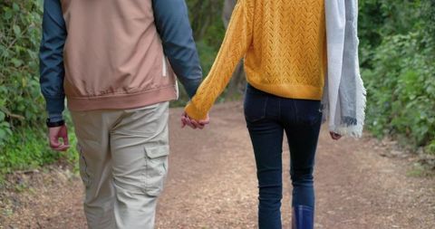 Couple Walking Hand-in-Hand on Woodland Trail Wearing Jacket Scarf Casual Fall Stroll